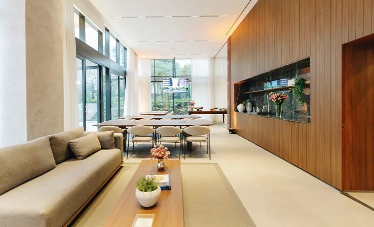 Lobby do ÁMPIO com sofá, mesa comprida e painel de madeira