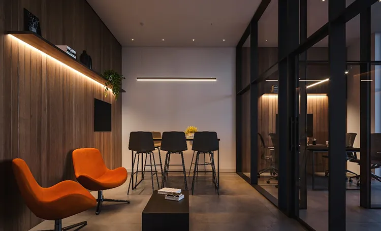 Sala de reuniões com poltronas laranja e paredes de madeira