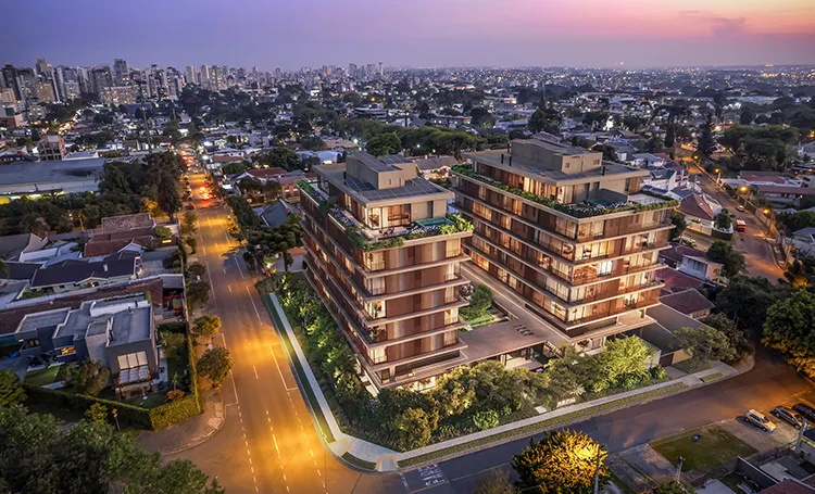 Vista aérea de dois edifícios residenciais em rua iluminada ao anoitecer
