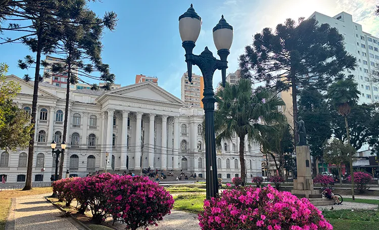 Praça com prédio histórico e azaleias em Curitiba