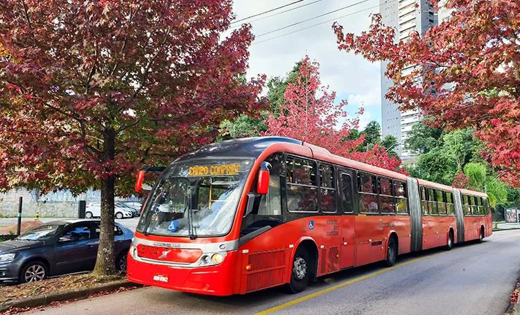 Ônibus vermelho articulado em rua de Curitiba