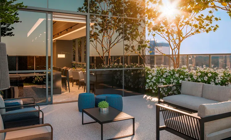 Terraço com sala externa, sofás e jardim ao entardecer