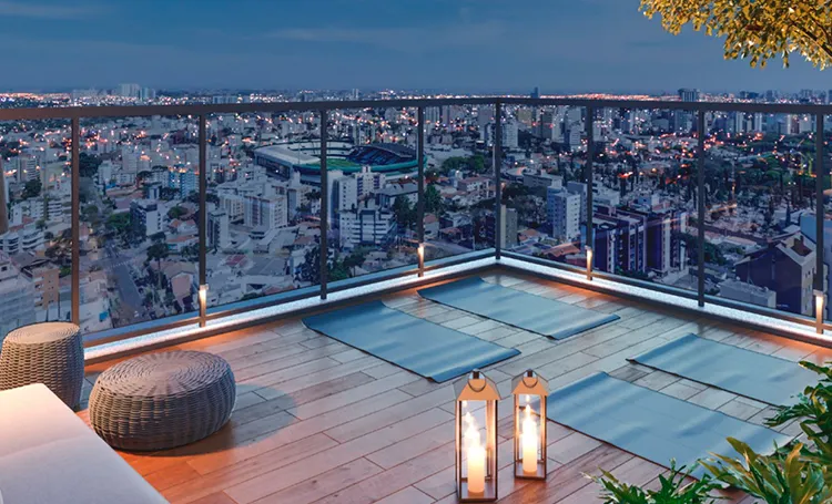 Terraço com deck e pufes sobre a cidade ao entardecer