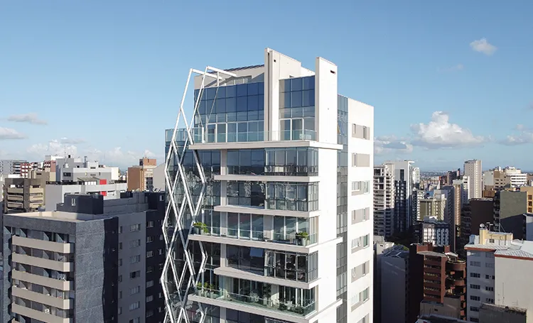 Torre do Llum com fachada de estrutura branca vista entre prédios de Curitiba
