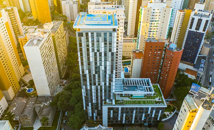 Vista aérea de torre com cobertura verde e piscina entre prédios
