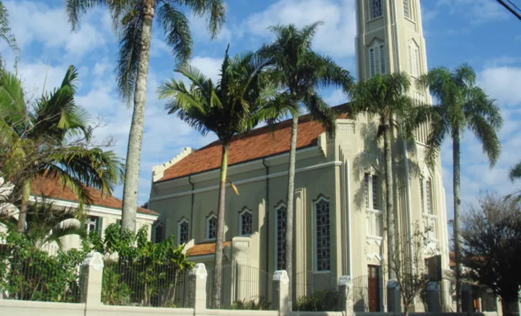 Igreja com torre e palmeiras em Curitiba