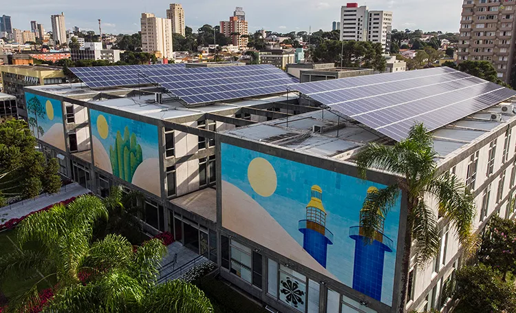 Vista aérea de edifício com painéis solares no telhado e murais coloridos na fachada