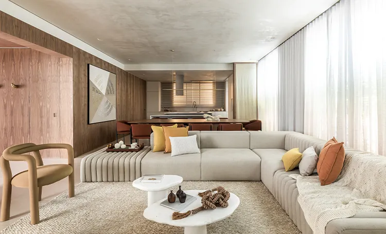 Sala de estar com sofá modular, poltrona e cozinha ao fundo