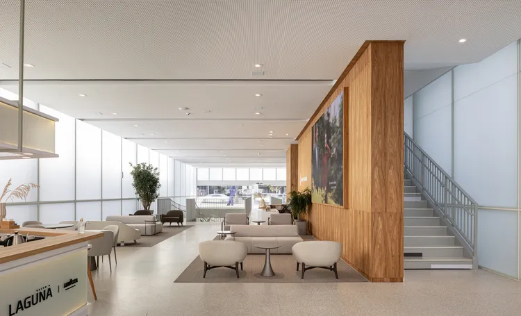 Salão da Galeria Laguna com sofás, escada e painel de madeira