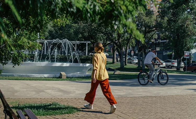 Mulher caminhando e ciclista na Praça da Espanha, em Curitiba