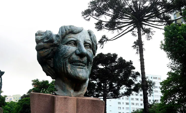 Busto de bronze com araucária ao fundo, em Curitiba