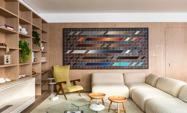 Sala com estantes, quadro colorido e sofá claro