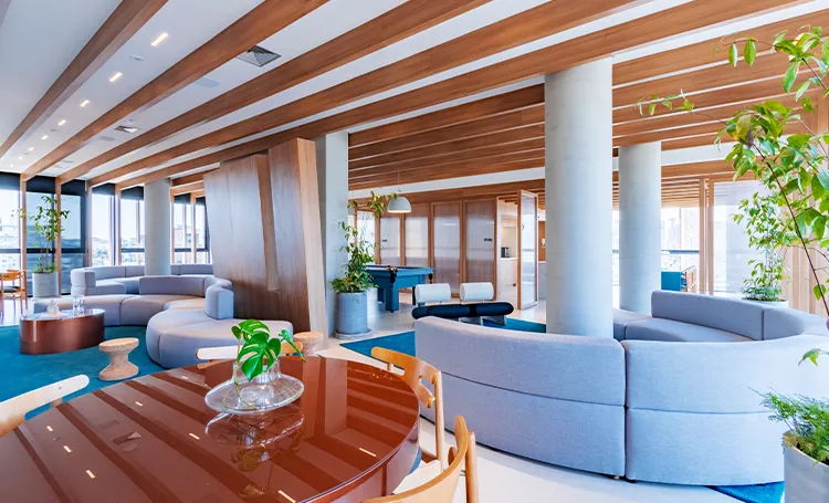 Clubhouse do VAZ Batel com vigas de madeira, colunas e sofás em curva