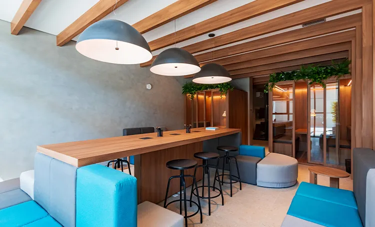 Coworking do VAZ Batel com bancada de madeira, banquetas e luminárias