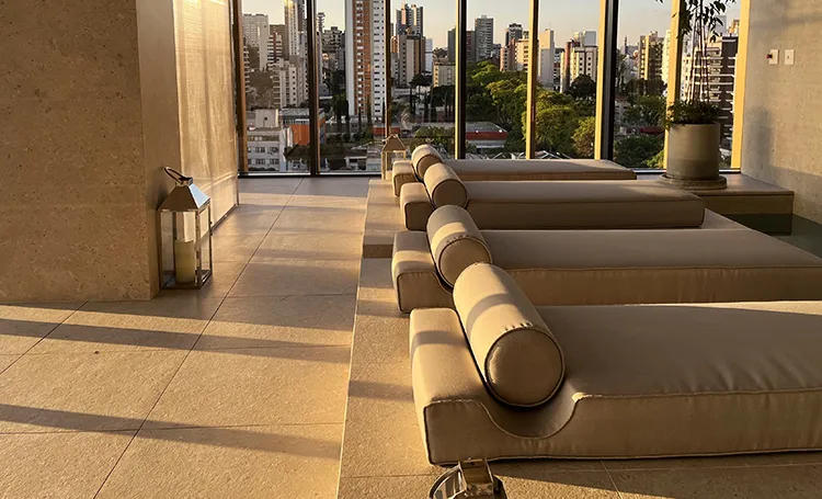 Sala de repouso do spa com chaises e vista dos prédios de Curitiba