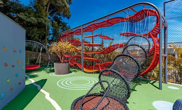 Playground do Mai Terraces com rede de cordas vermelha e parede de escalada