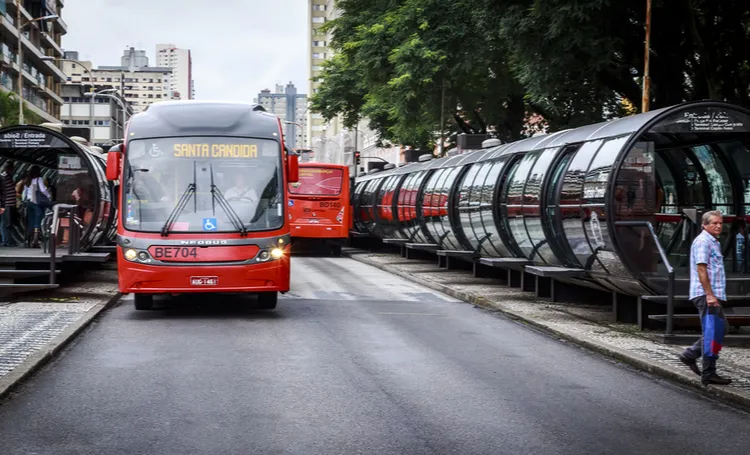 Ônibus vermelho e estação tubo na rua de Curitiba