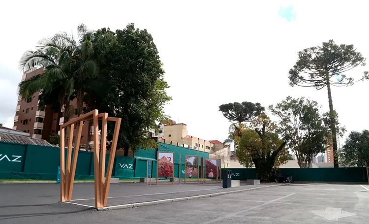 Praça com escultura de cobre e tapume do VAZ ao fundo