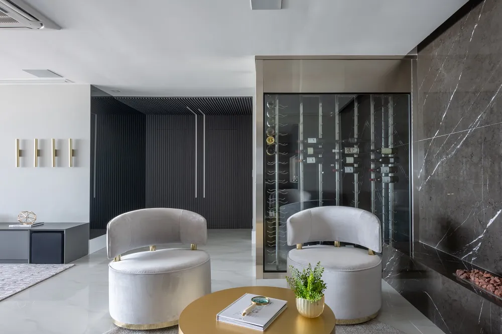 Sala de estar com poltronas claras e adega envidraçada ao fundo