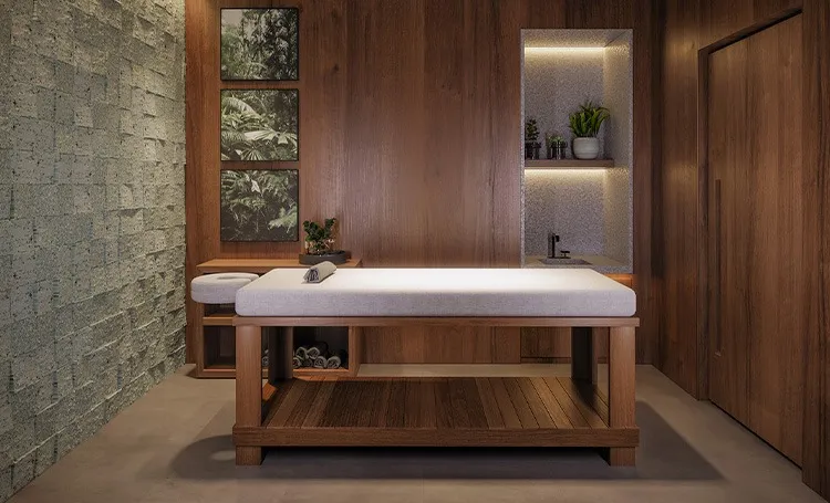 Sala de massagem com maca de madeira e parede de pedra, no PINAH
