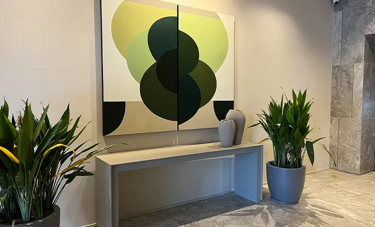 Quadro de formas verdes no hall do PINAH, com vasos de plantas