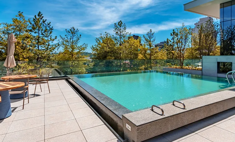 Piscina externa com deck e árvores, em empreendimento da Laguna