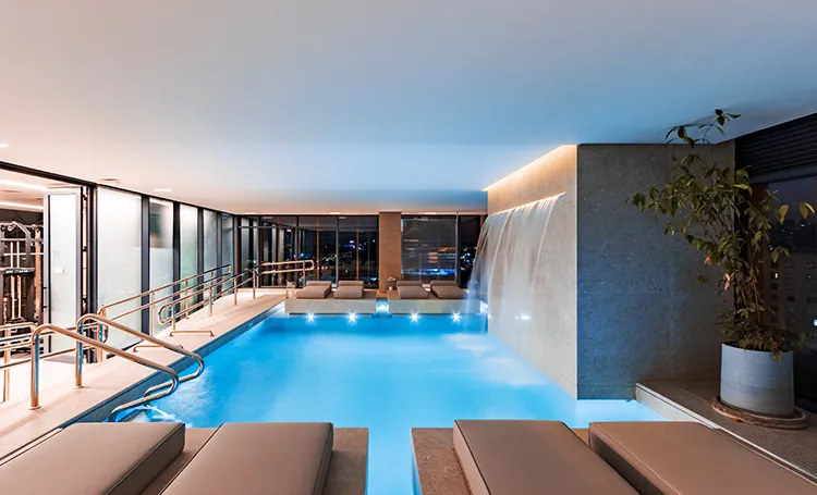 Piscina coberta aquecida com cascata e espreguiçadeiras
