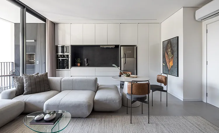 Sala com sofá modular, cozinha integrada e mesa redonda