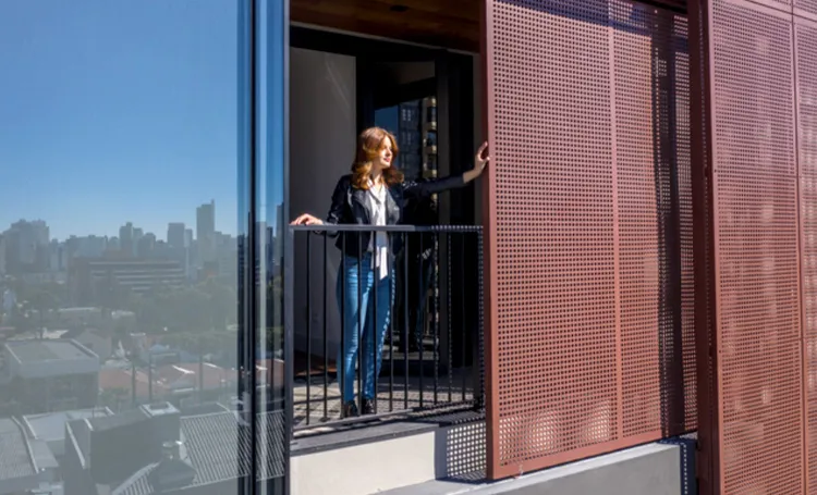 Mulher em varanda com brise vermelho e vista de prédios de Curitiba