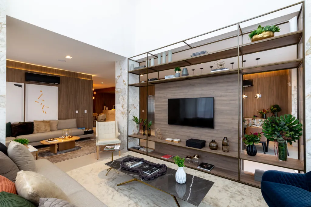 Sala com estante metálica, painel de TV e mesa de centro em mármore