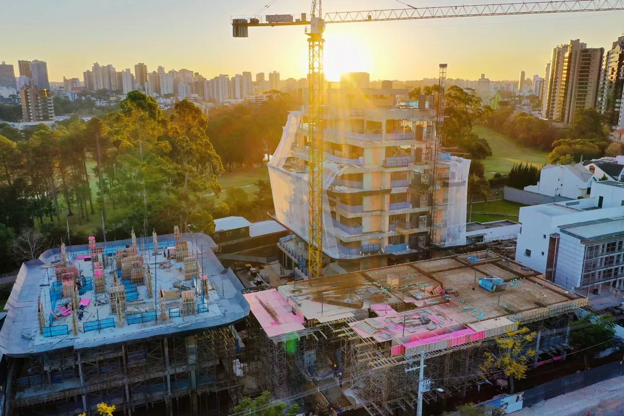 Obra ao pôr do sol com grua e torre em construção, ALMÁA Cabral