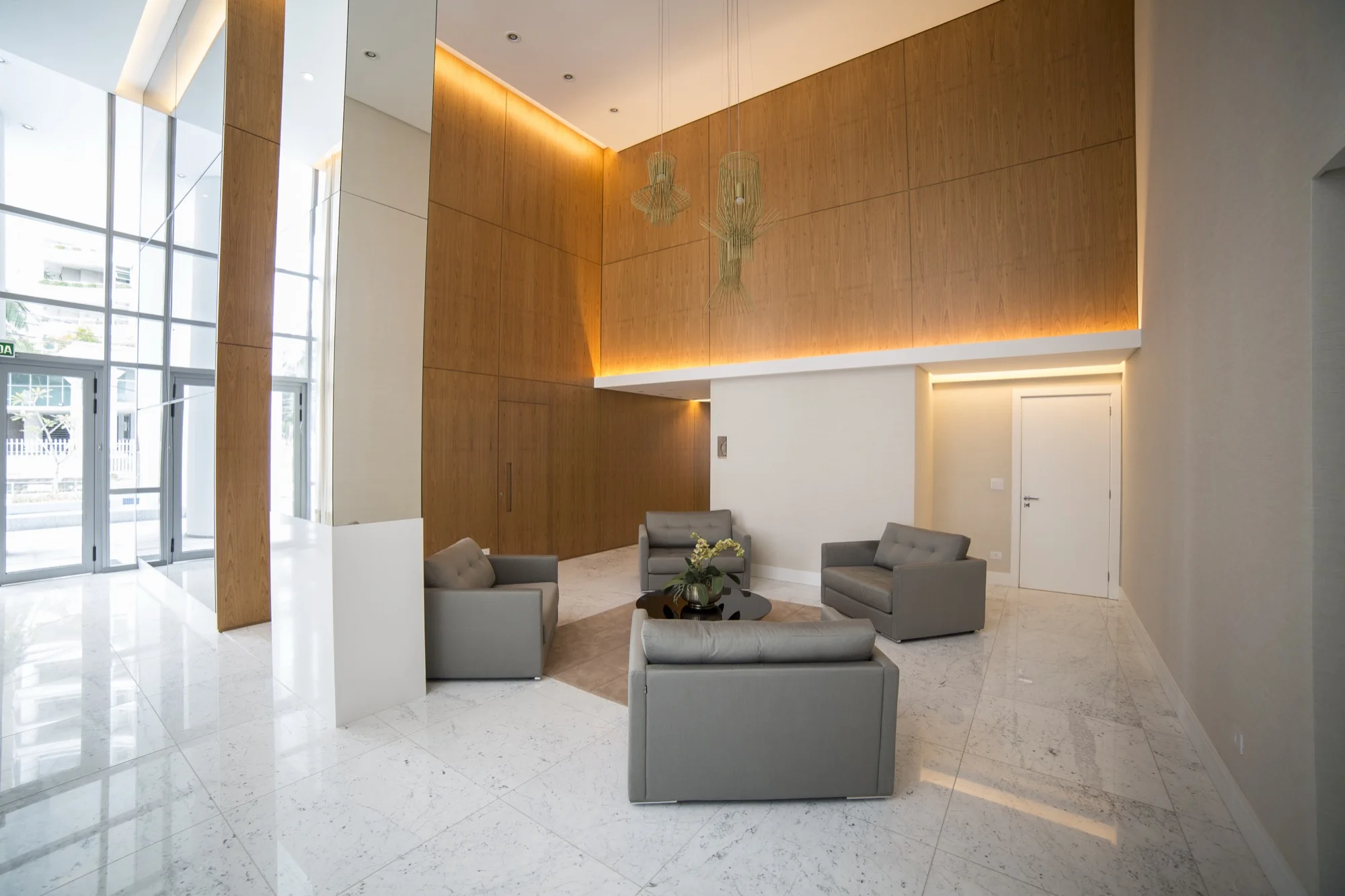 Hall de entrada com painel de madeira e sofás no EOS Barigui