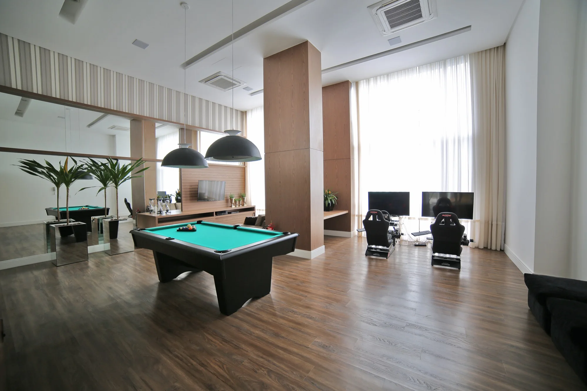 Sala de jogos do EOS Barigui com mesa de bilhar e simuladores