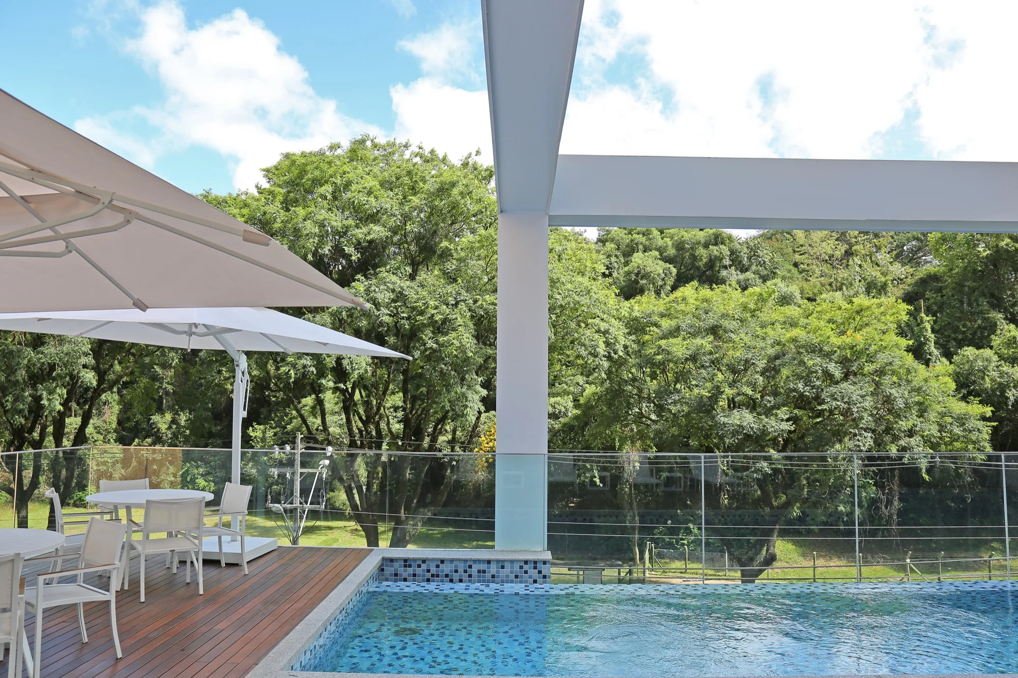 Piscina externa com deck e árvores ao fundo no EOS Barigui