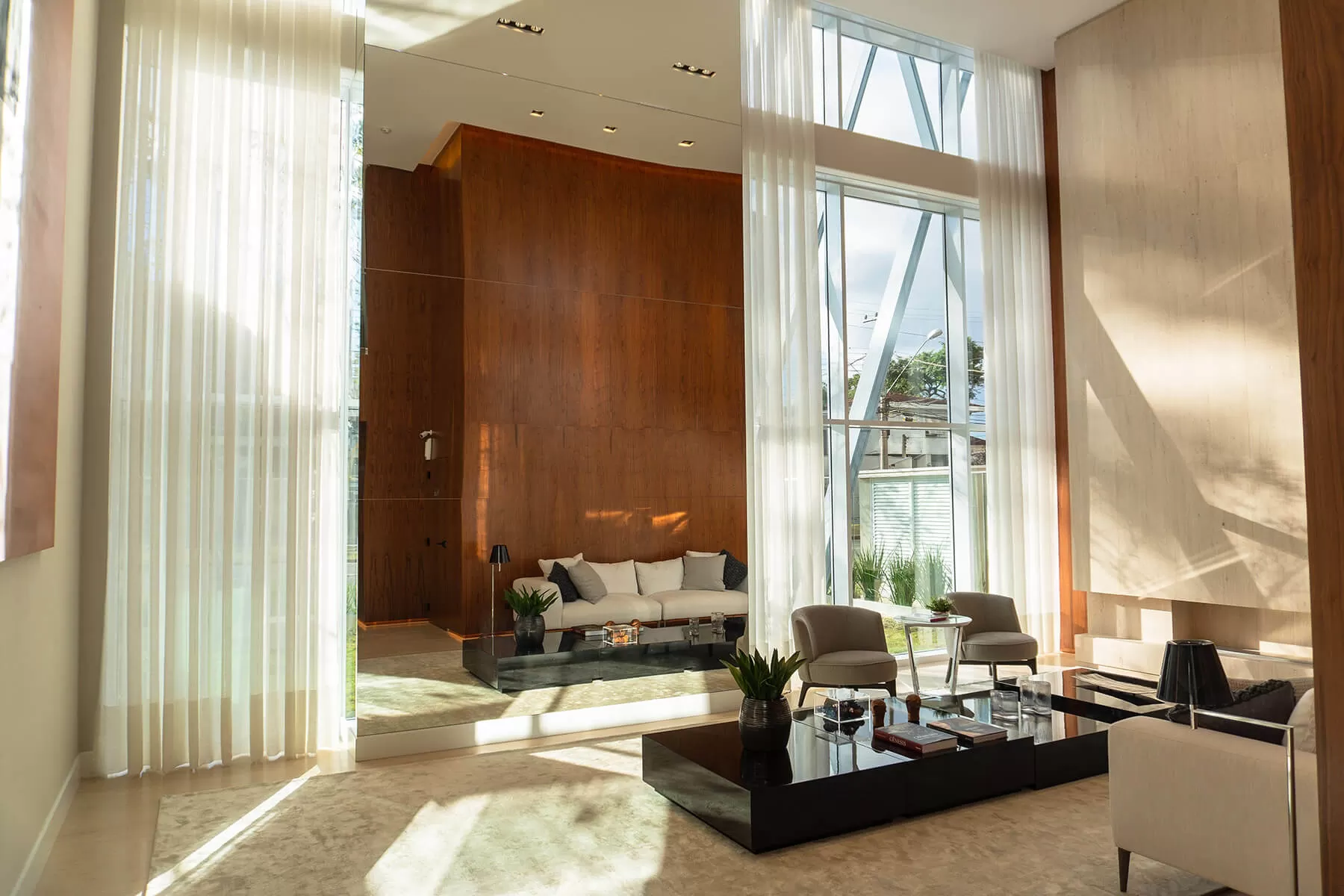 Hall de pé-direito alto com sofás e cortinas, LLUM Batel