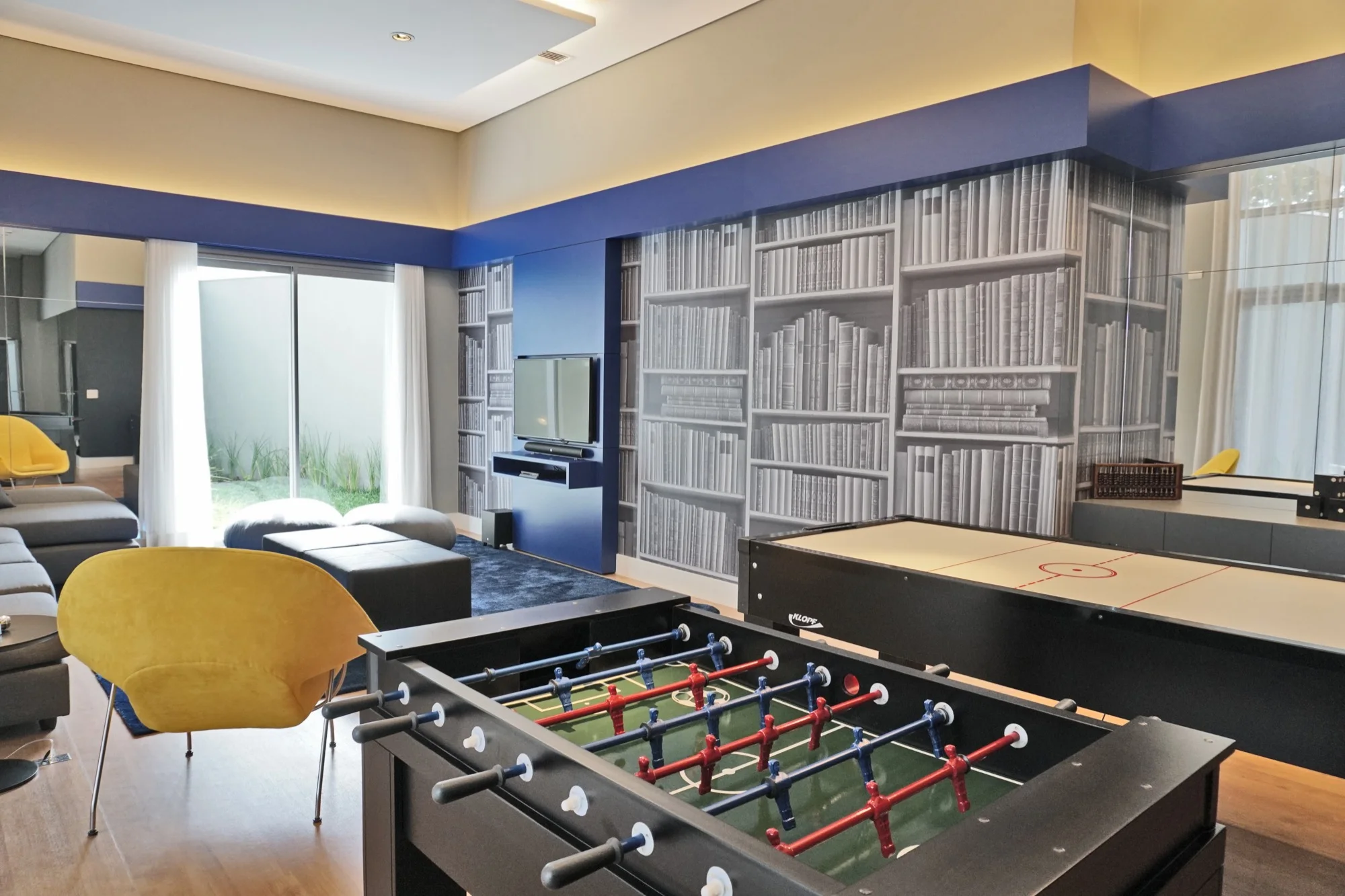 Sala de jogos do MAI Home com pebolim e estante ilustrada