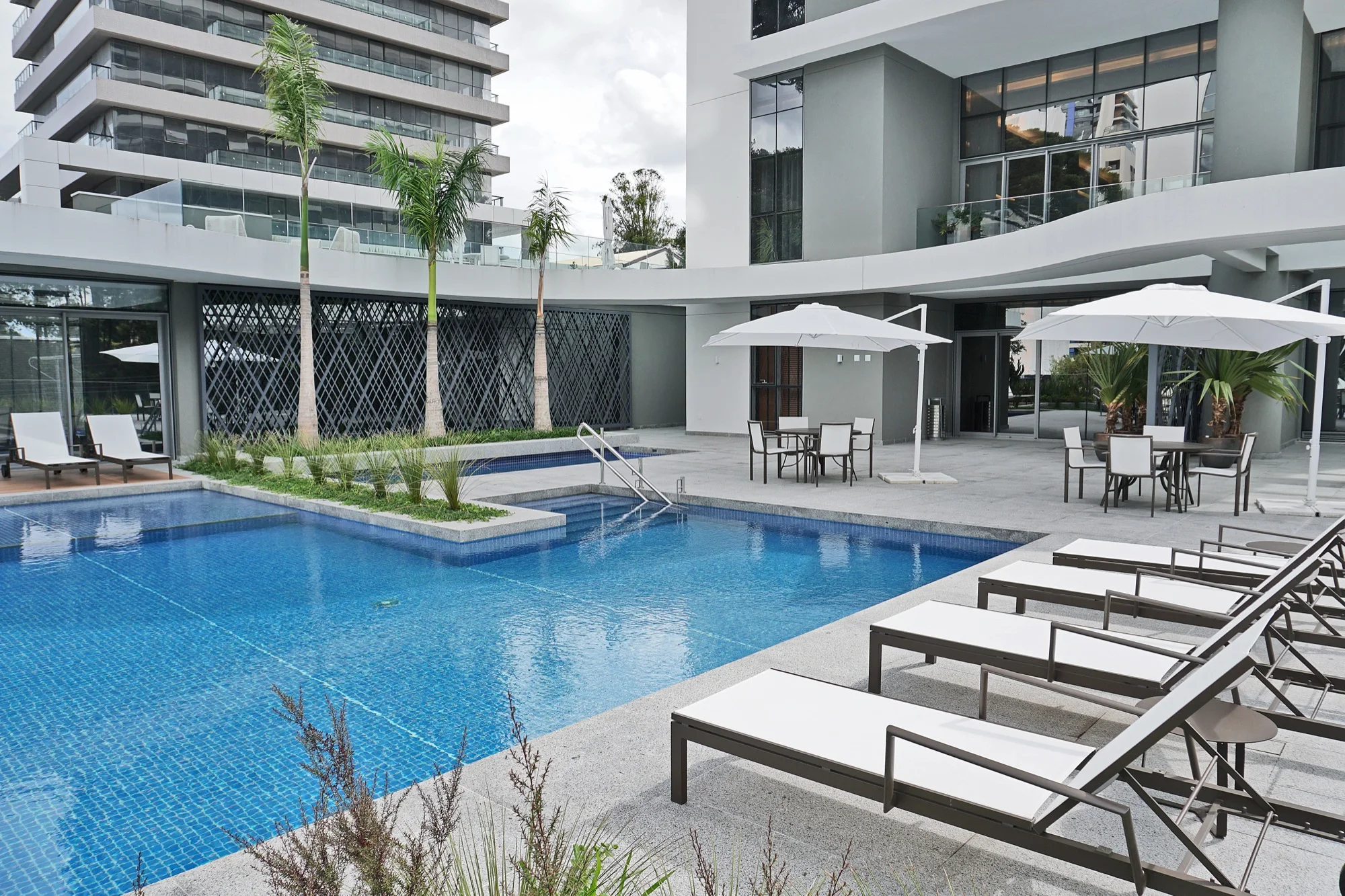 Piscina com guarda-sóis e fachada curva no MAI Home