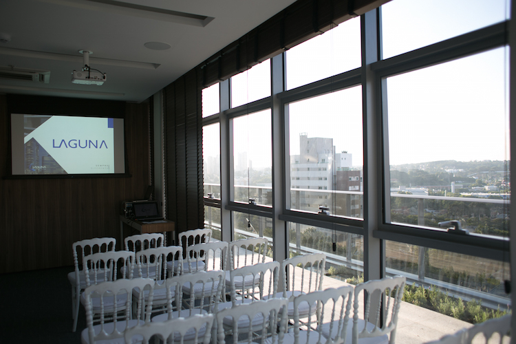 Sala de reuniões do MAI Work com cadeiras brancas e telão da Laguna