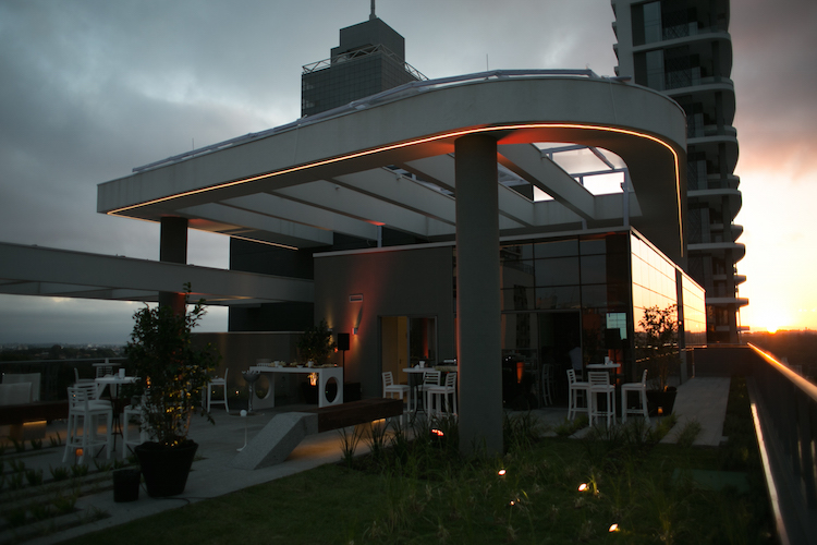 Terraço do MAI Work ao pôr do sol, com cobertura curva iluminada