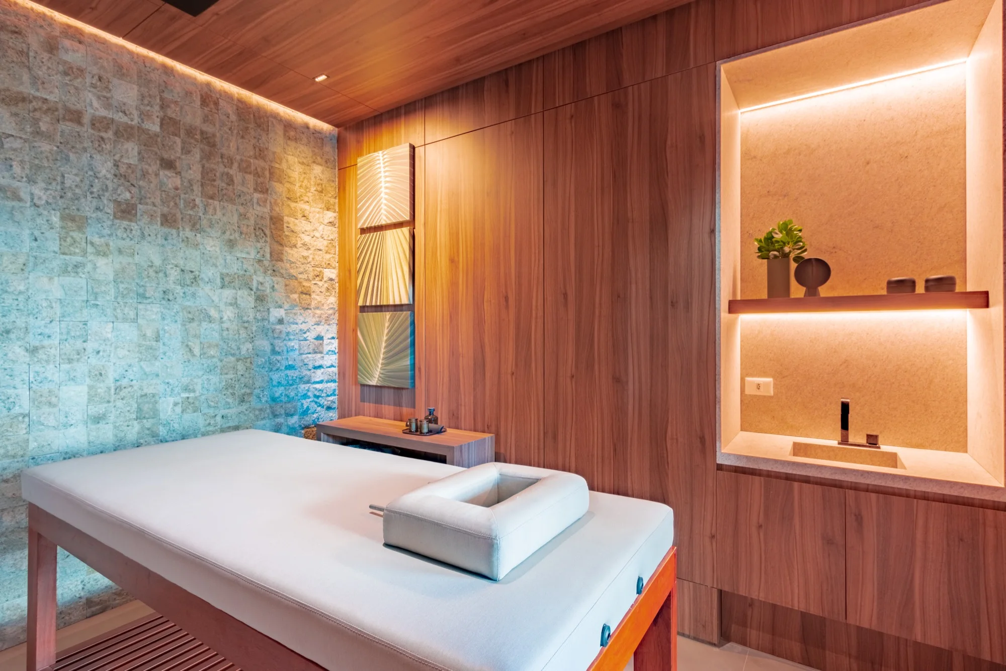 Sala de spa com maca e parede de pedra no PINAH