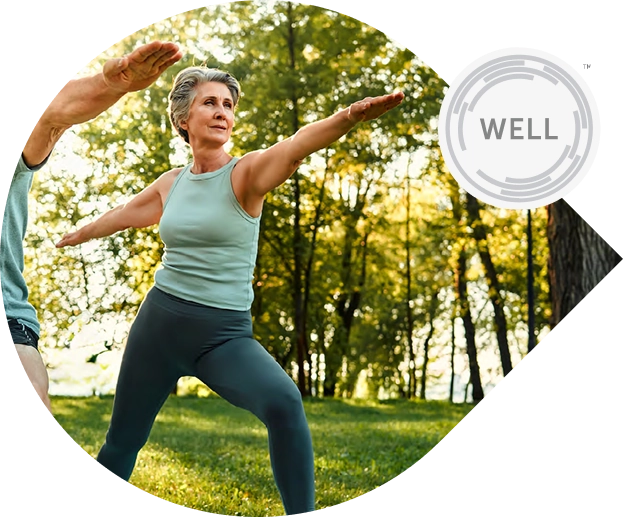 Mulher madura praticando alongamento em área verde, representando o estilo de vida ativo e saudável inspirado pelo residencial BIOOS Barigui